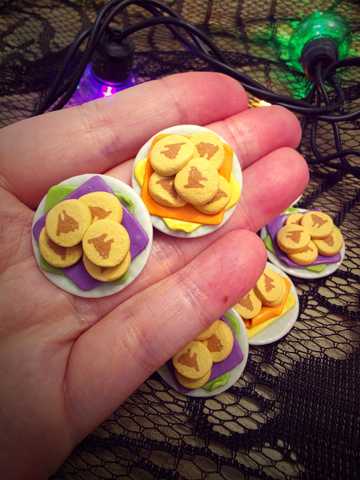 Hand holding tiny Halloween cat cookie plates to show their miniature size