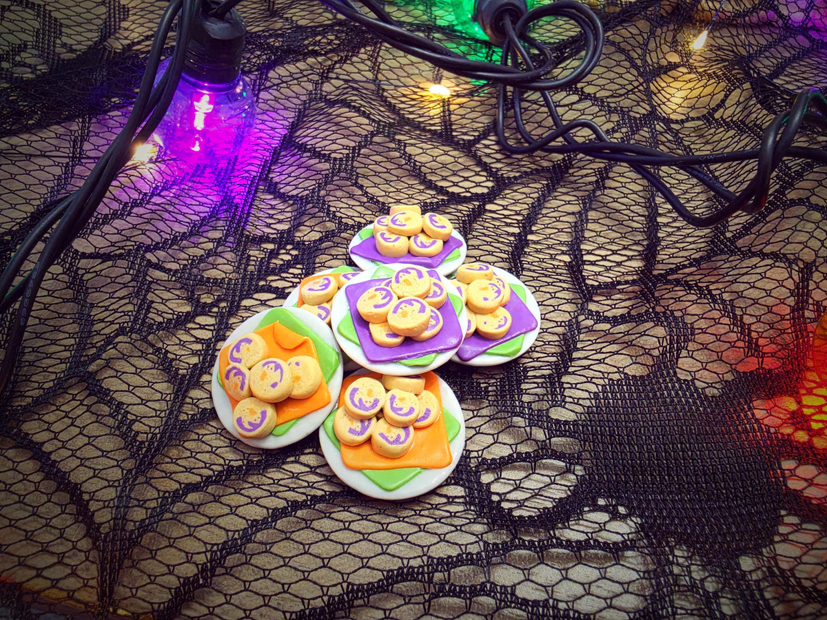 Miniature Halloween ghost cookie plates styled on spiderweb lace with glowing string lights
