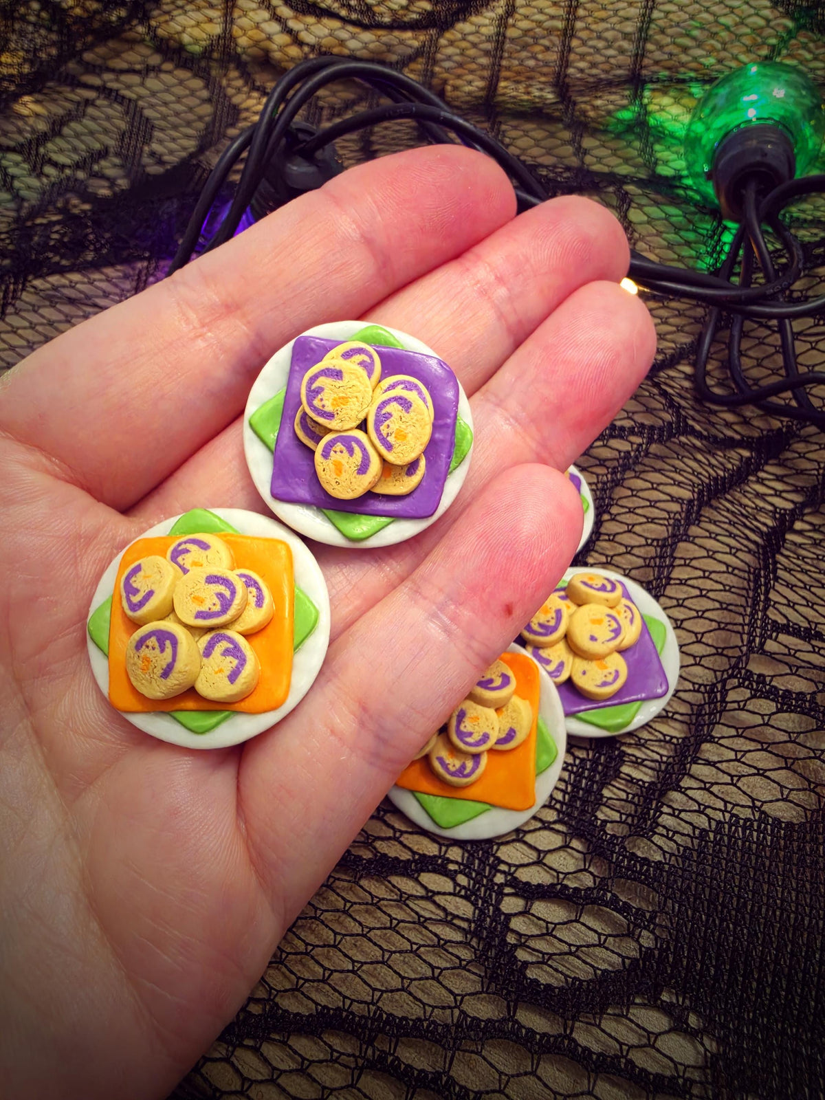 Hand holding tiny Halloween ghost cookie plates to show their miniature size