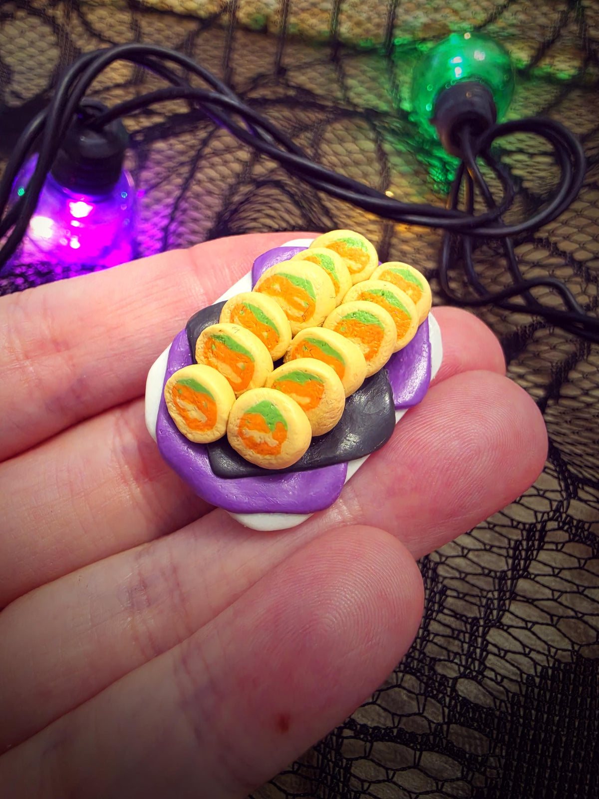 Hand holding the tiny pumpkin cookie platter to show its miniature size