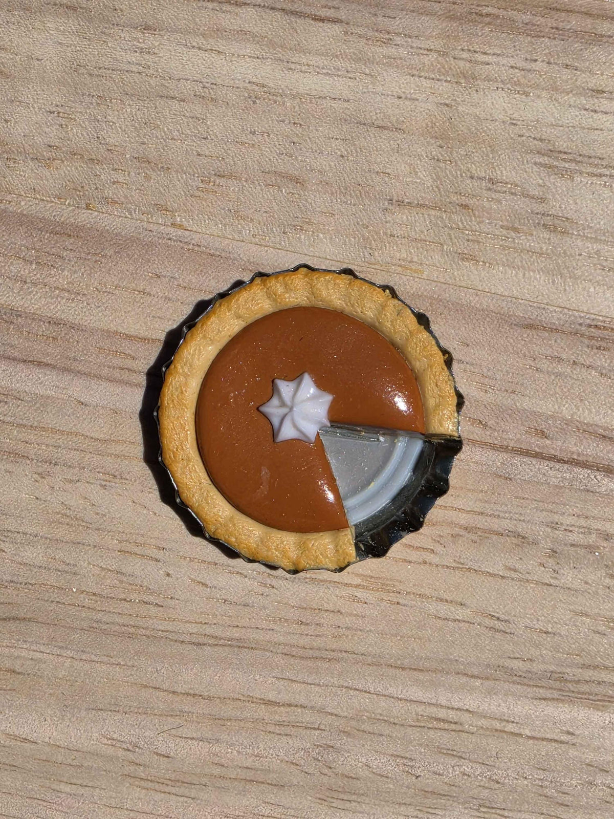 Top view of a mini pumpkin pie magnet made from polymer clay, with a slice missing